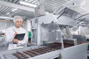 chocolate factory man worker inspecting production line conveyor with sweets candy